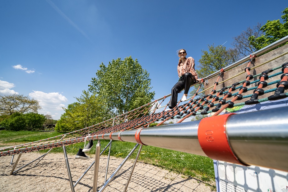 Eine Besucherin sitzt auf dem geschwungenen Klettergerüst der Station Strahlstrom. © Stadt Offenbach / Frank Rumpenhorst